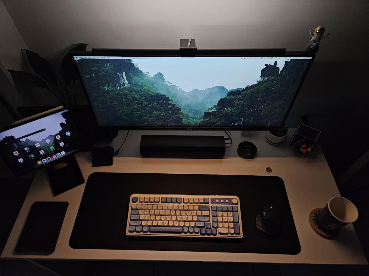 Modern home office desk with keyboard, widescreen monitor, and tablet, creating an ideal productivity setup.