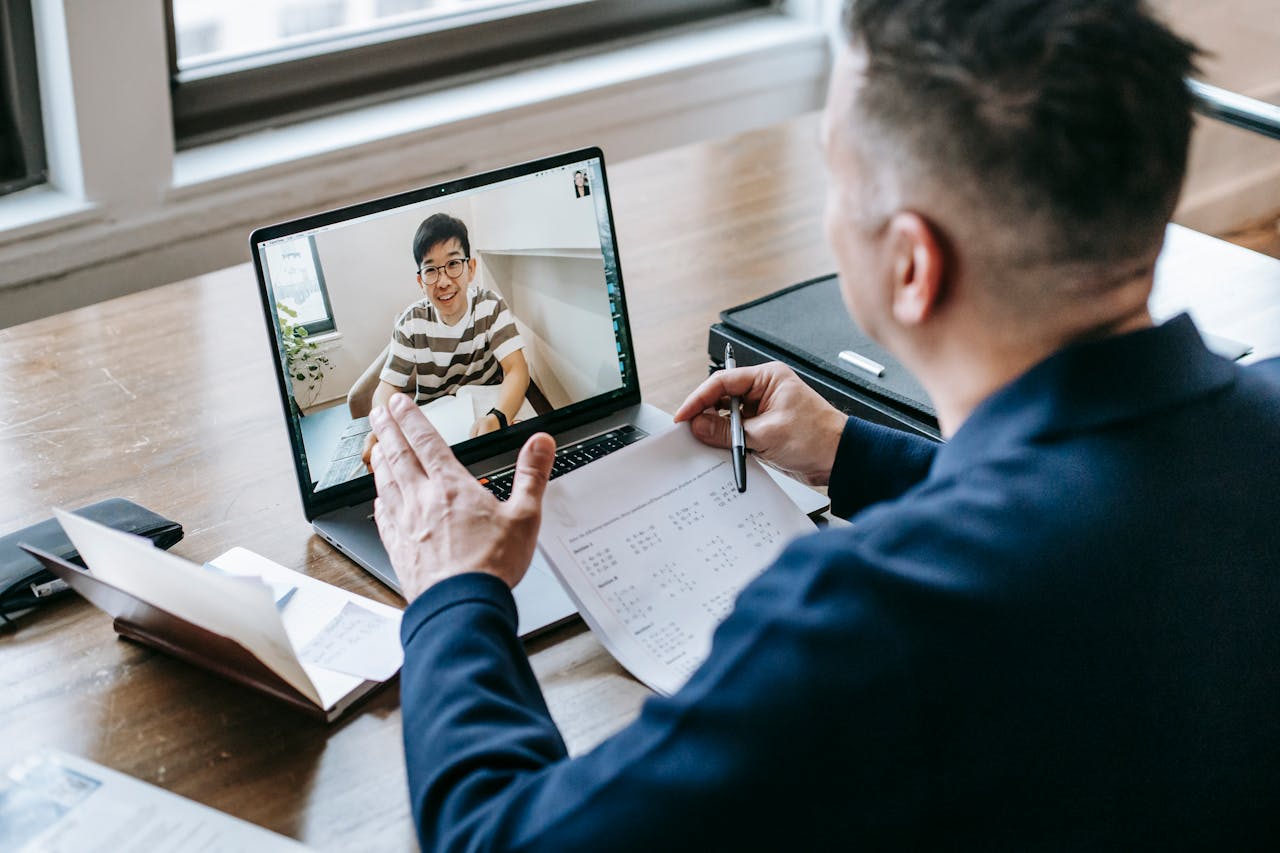 A professional having a video conference on a laptop from a home office, engaging in online communication.
