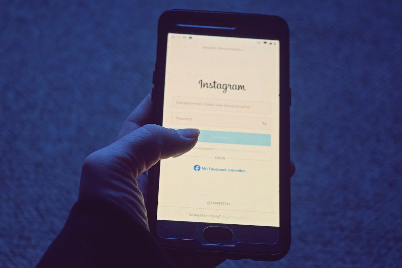 Close-up of a hand holding a smartphone displaying the Instagram login screen.